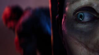 A Senua's Saga: Hellblade 2 screenshot showing a close-up of Senua's eye while the blurry shape of a roving creature can be glimpsed behind her.