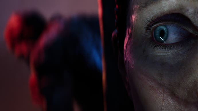 A Senua's Saga: Hellblade 2 screenshot showing a close-up of Senua's eye while the blurry shape of a roving creature can be glimpsed behind her.