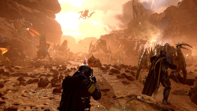 A Helldivers 2 screenshot showing players battling armies of scuttling and flying aliens on a hostile desert planet.