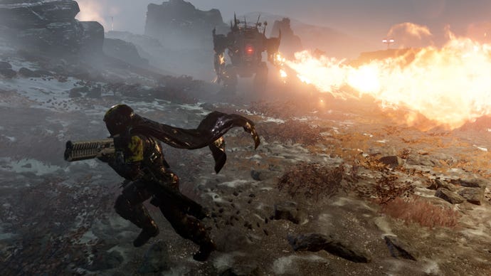 Helldivers 2 screenshot showing a player character in a futuristic military suit with a cape, holding a gun, running away from a large robot firing a flamethrower on a rocky planet.