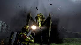 Two people in futuristic suits of armour are shooting at a very large bug-like alien, both of them covered in its green blood in Helldivers 2.