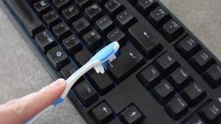 A keyboard being dusted with a toothbrush.