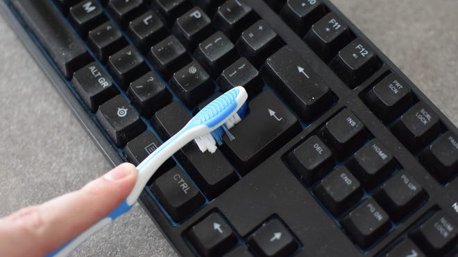 A keyboard being dusted with a toothbrush.