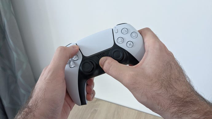 A PS5 controller, with the user’s hands holding down the PS and Share buttons to initiate Bluetooth pairing.