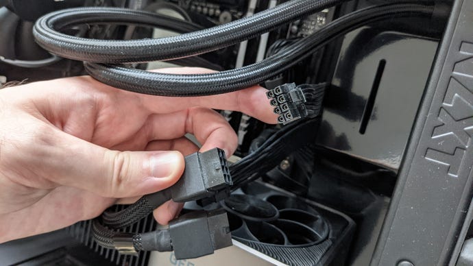 A PCIe power cable being held up next to Nvidia’s RTX 30 series power adapter.