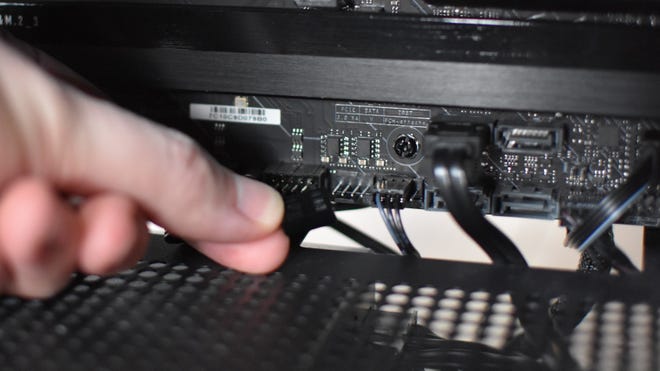 A case fan cable about to be connected to a motherboar fan header.