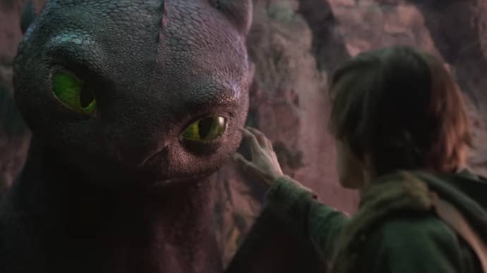 A teenage boy reaches his hand out towards a suspicious black dragon in the live action version of How to Train Your Dragon.
