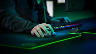 a photo of a gamer holding a razer viper ultimate mouse at a desk festooned with rgb lighting