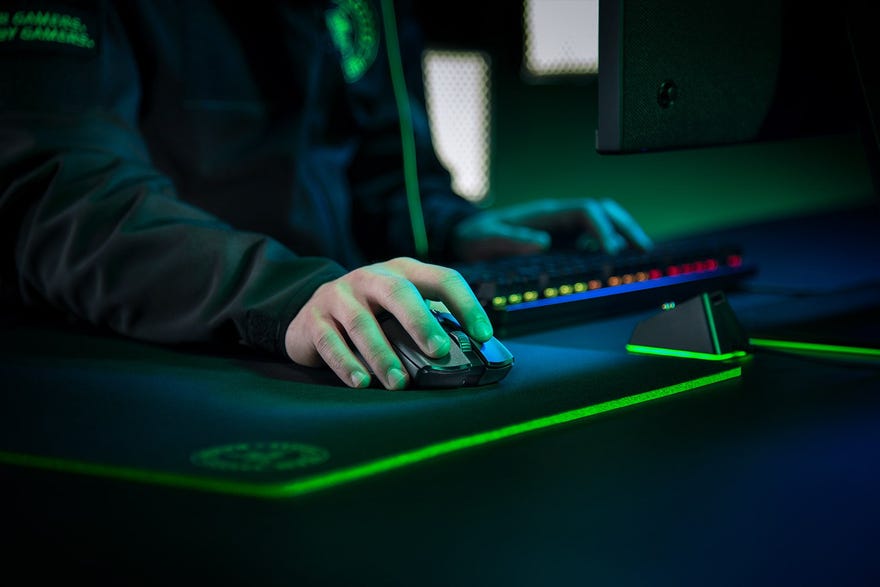 a photo of a gamer holding a razer viper ultimate mouse at a desk festooned with rgb lighting