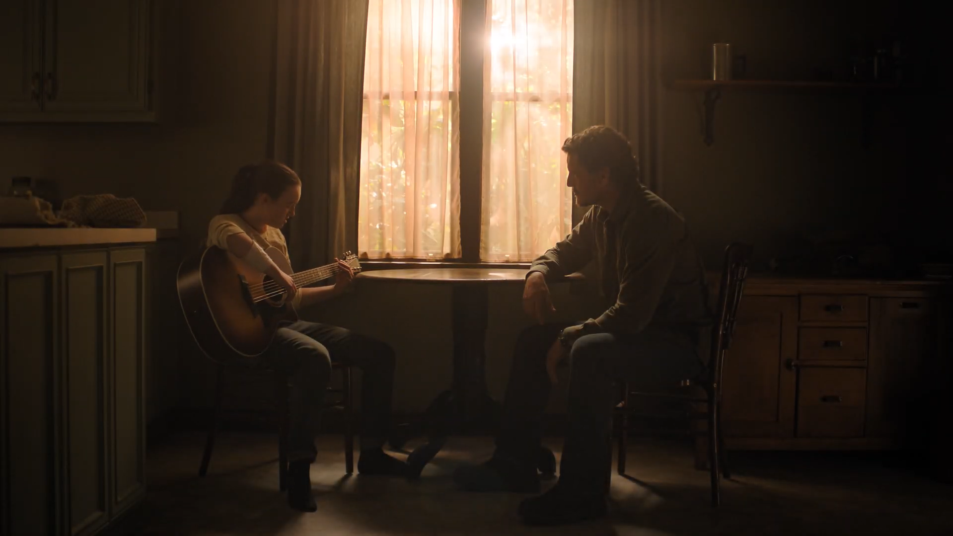 Ellie plays the guitar as Joel watches in TLOU season two