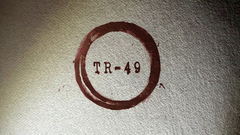 What looks like a close-up photograph of a page in a book. The title TR-49 is ringed in red, and the heavy parchment of the page is cloaked in a darkness that surrounds the image.