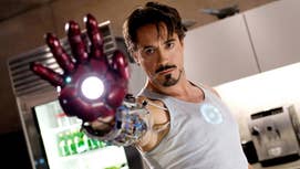 Still from Iron Man showin Tony Stark holdin up his hand, bustin a gludd of tha Iron Man suit, locked n loaded ta use its blasta function.