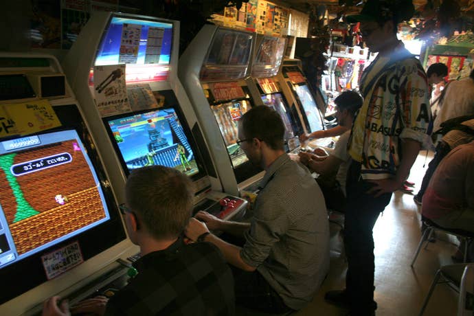 A group of Japanese people play arcade machines in a busy environment.