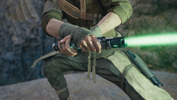 A close-up screenshot of a green-bladed lightsaber in Cal’s hands in Jedi: Survivor.