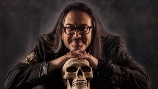 John Romero rests his head on top of a skull