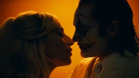 A still from Joker 2 showing Lady Gaga and Joaquin Phoenix as Harley Quinn and The Joker about to kiss, silhouetted by an orange light.