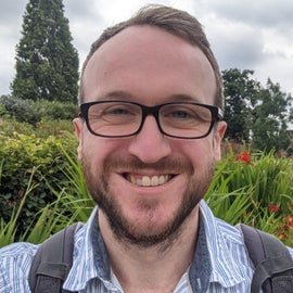 朱利安·本森的头部特写照片,站在花园里背着背包。