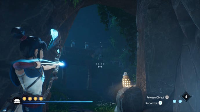 Kena shoots an arrow at a crystal from a cave mouth in Kena: Bridge Of Spirits.