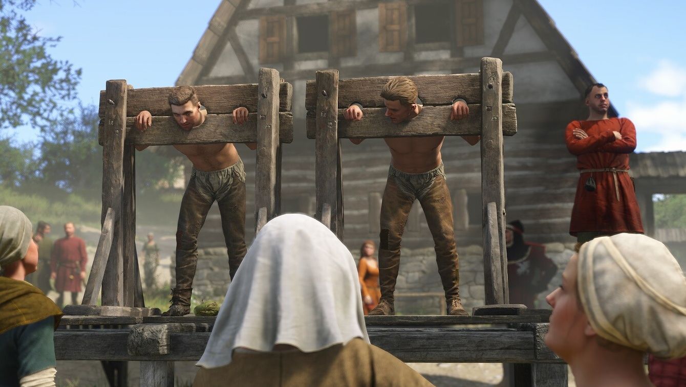 Two men are trapped in the stocks in a town square while a crowd looks on. - 1