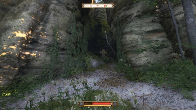 A stone cross and small altar tucked into an alcove beneath some large rocks in Kingdom Come Deliverance 2