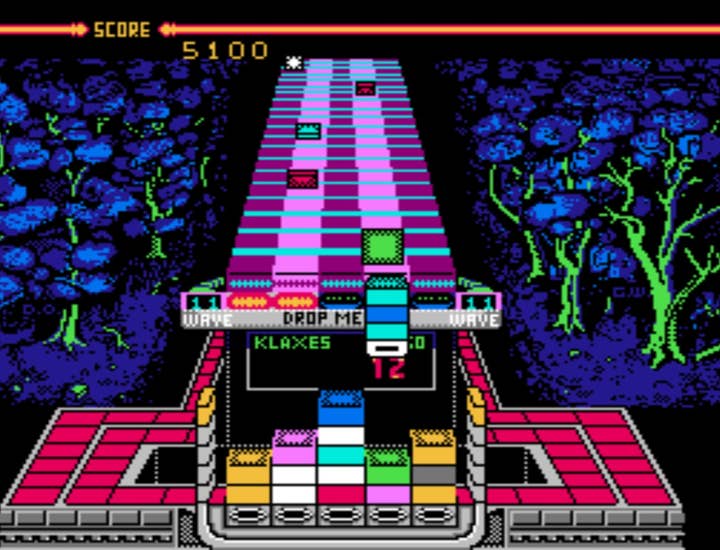 An image of the NES version of Klax, with a bunch of differently colored square tiles flipping down a belt toward the screen, and a playfield where the player has dropped the tiles to try and match up colors