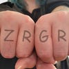 Outstretched fists displaying a mock-up knuckle tattoo: RAZRGRRL.