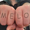 Outstretched fists displaying a mock-up knuckle tattoo: MEMELORD