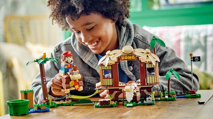 A teenager playing with Lego’s Donkey Kong Tree House set, complete with Lego Mario riding Donkey Kong.