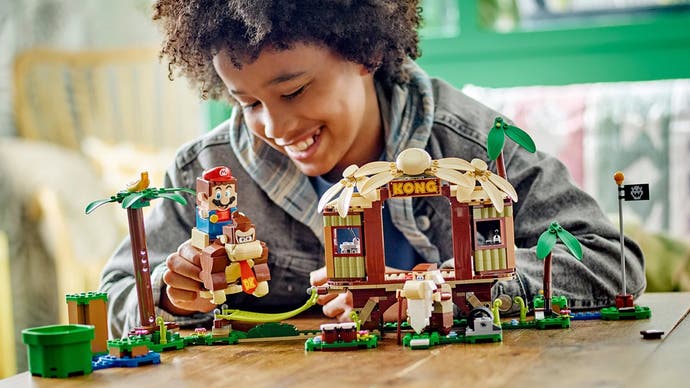 A teenager playing with Lego's Donkey Kong Tree House set, complete with Lego Mario riding Donkey Kong.