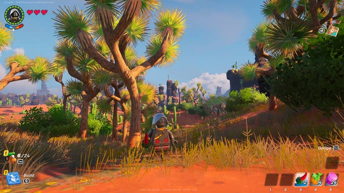 Lego Fortnite desert location: A lego man with a mask on is standing near a scrub tree in the middle of the desert.