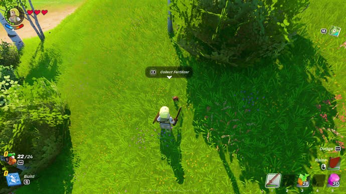 A LEGO Fortnite character prepares to pick up some fertiliser found in a grassy field.