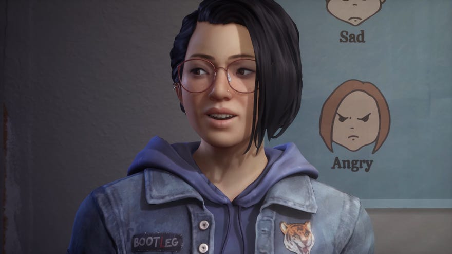 Life Is Strange: True Colors - Main character Alex Chen sits, talking, in front of a poster with drawn faces labeled “Sad” and “Angry”