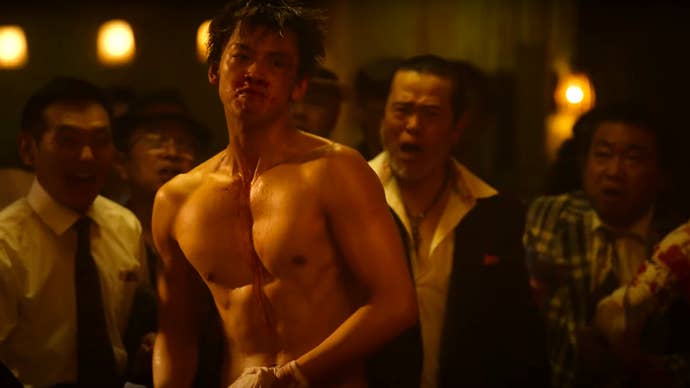 A character from Amazon’s Like a Dragon: Yakuza live-action series, shirtless and ready to fight as men gather around him shouting.
