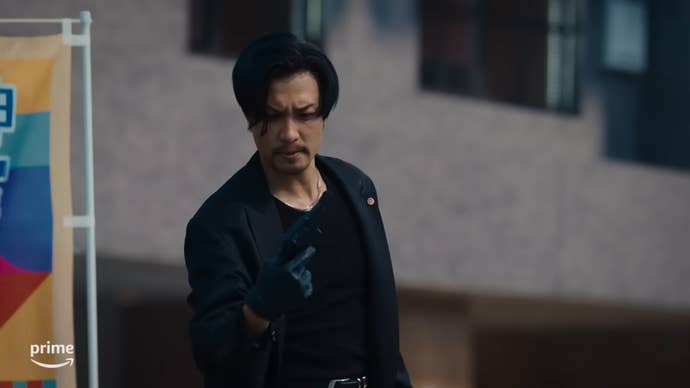 Live-action Goro Majima looking at a gun in his hand, confused, in Like a Dragon: Majima.