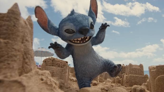Stitch, a blue, dog-like alien is stomping on some sand castles in the live-action Lilo & Stitch remake.