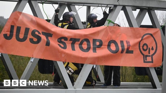 A Just Stop Oil banner hanging from a gantry over M25