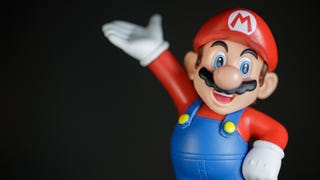 A macro-photography image of a plastic Mario figurine. Mario holds his hand up as if holding an invisible waiter's tray, albeit quite high in the air (he'll drop something for sure).
