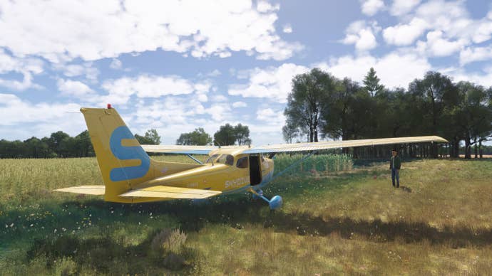 A pilot stands next to their yellow plane in a lovely field.