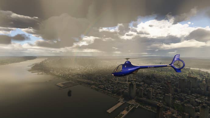 A blue helicopter flies over a rainy city.