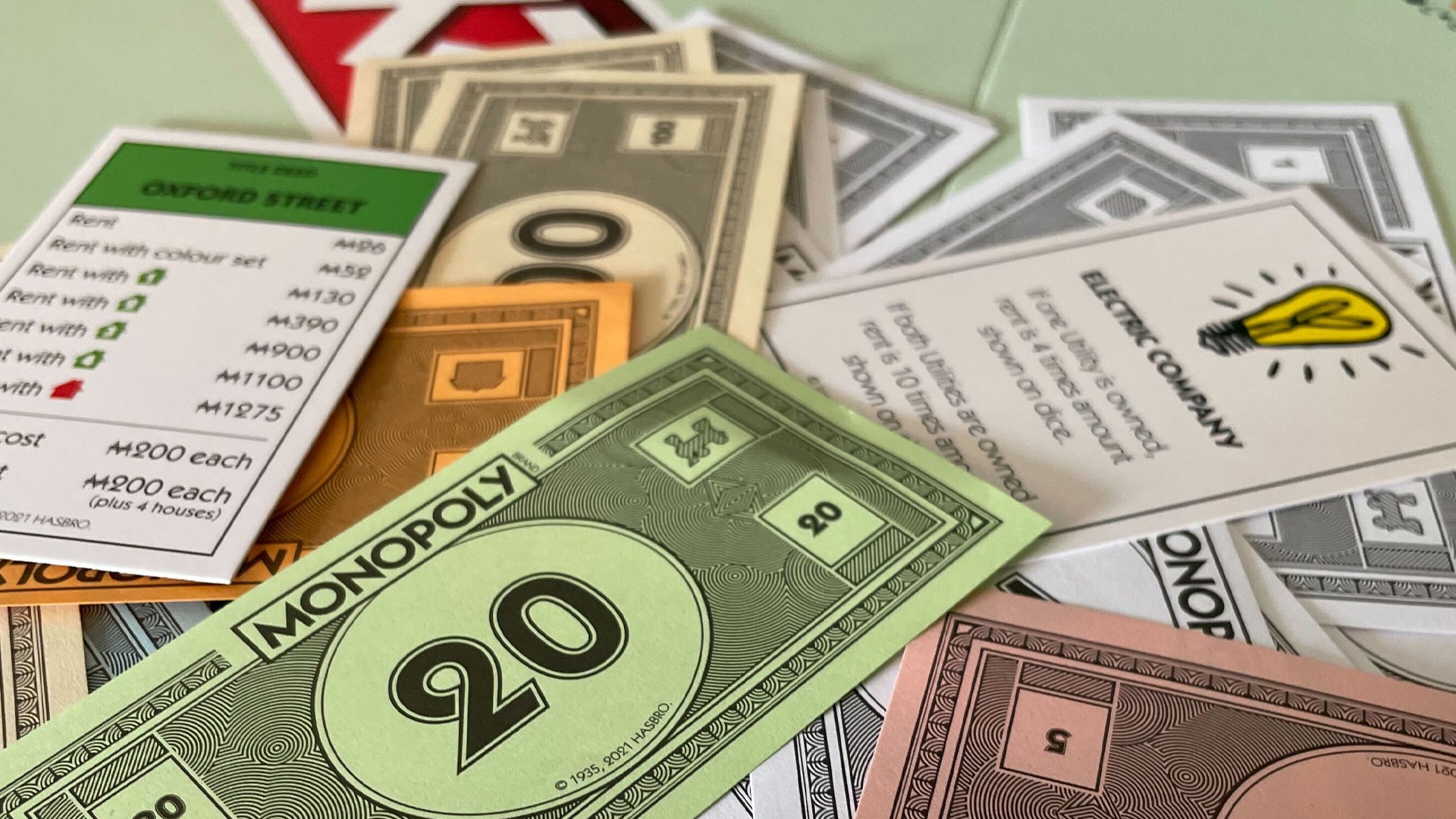 A pile of Monopoly money along with a few cards for property and utilities.