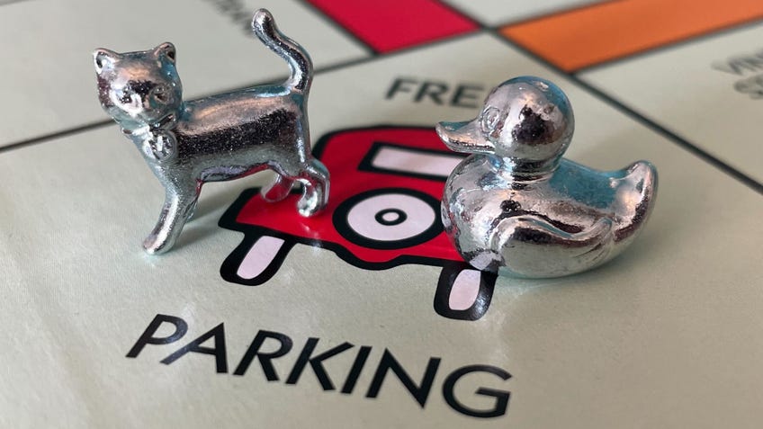 The silver cat and rubber ducky player tokens on the Free Parking square on the Monopoly board.
