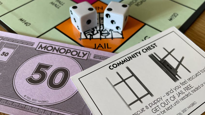 The Go To Jail square on the Monopoly board, along with two dice that have rolled a double, a $50 note and a Community Chest card.