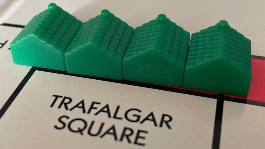 Four green houses placed in a row on the Trafalgar Square tile on the Monopoly board.