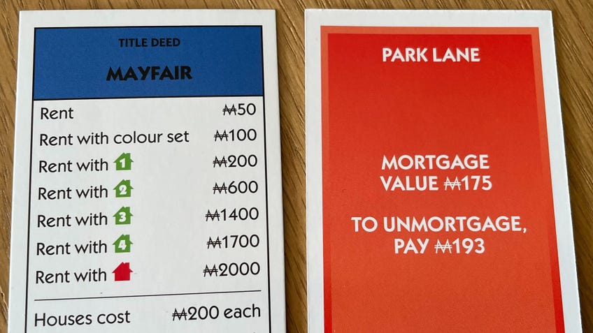 Monopoly property cards showing the title deed for Mayfair and how much it costs to mortgage Park Lane.