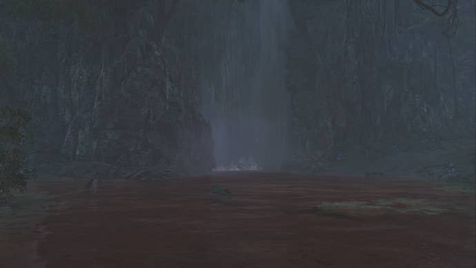 The player hunter in Monster Hunter Wilds looks towards a large waterfall in the Scarlet Forest, behind which lies the entrance to a hidden cave.