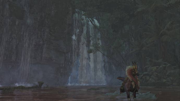 The player hunter in Monster Hunter Wilds looks towards a large waterfall in the Scarlet Forest, behind which lies the entrance to a hidden cave.