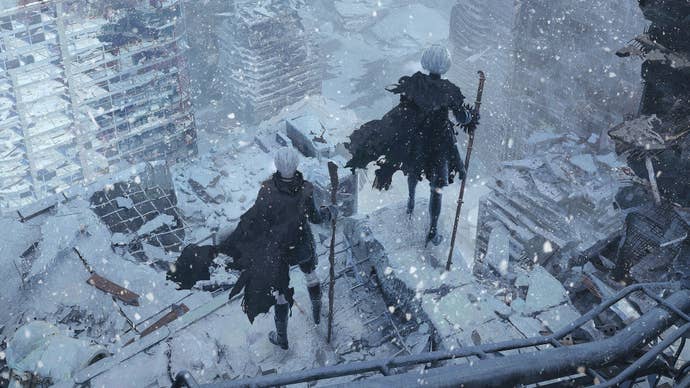 Nier Automata’s 9S and 2B stood holding pipes on top of a dilapidated building, looking down at a city, snow covering all the buildings around them.