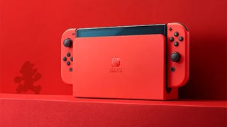 A product shot of a Mario red Switch OLED against a red wall with a silhouette of Mario nearby.