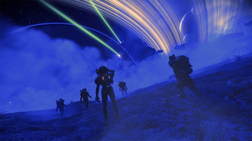 No Man’s Sky - Several players walk across the surface of a desert planet at night, looking up at two starships flying past the planet’s rings above.