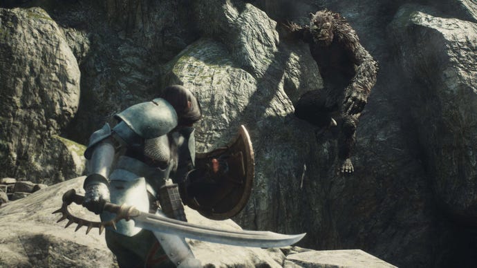 An ogre hanging off a cliff, glaring at a guy with a sword in the foreground